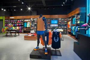 Manichini con abbigliamento running Nike arancione e blu su basamento espositivo in legno