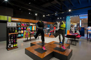 Dettaglio delle pedane espositive con manichini running in movimento, abbigliamento nero e fluo