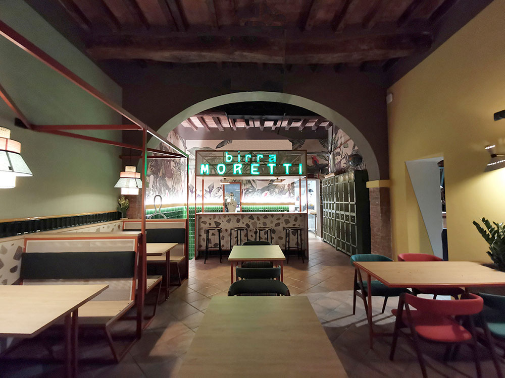 Gustavo's pizza | Vista frontale della sala con punto focale sul bancone con insegna vintage