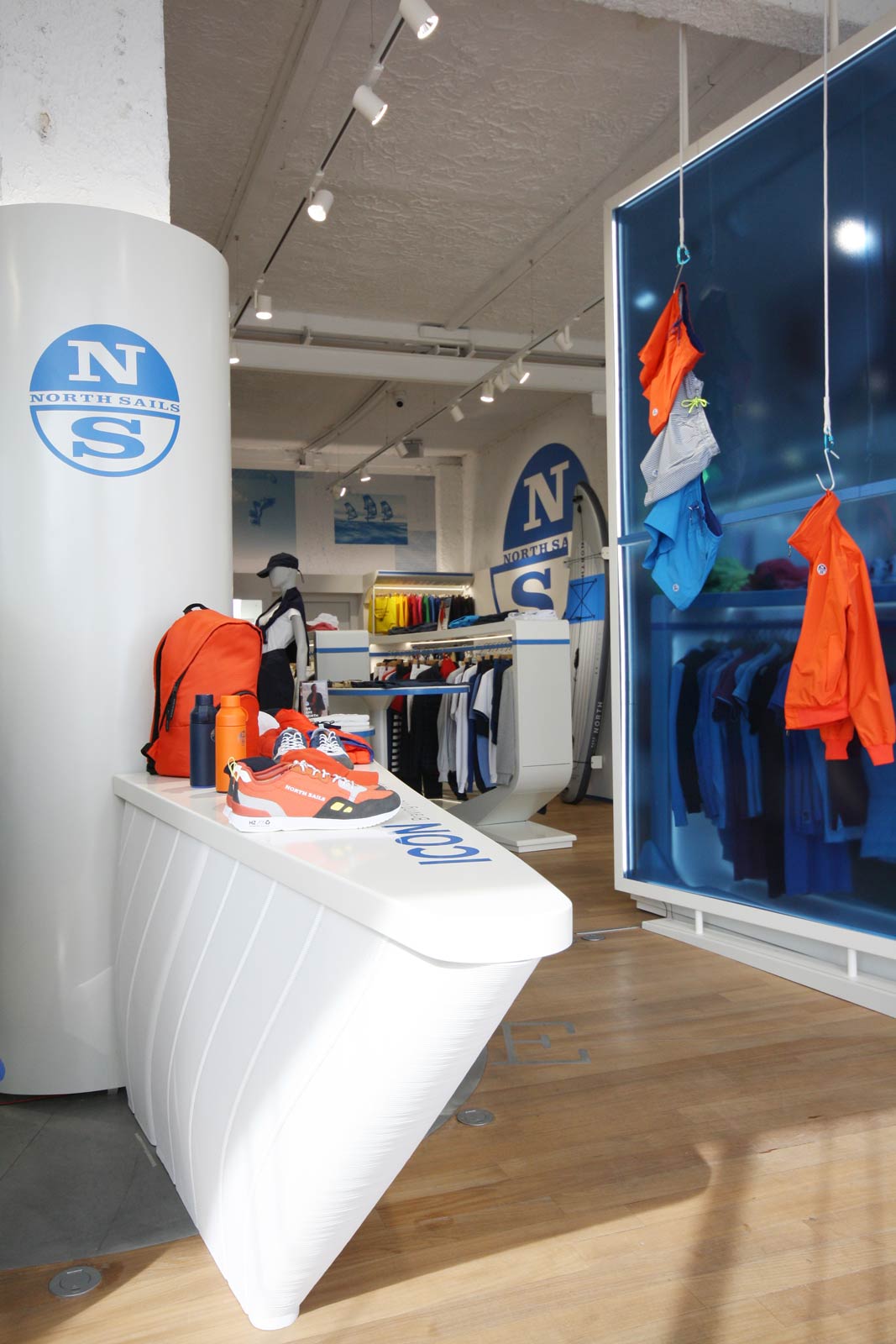North Sails flagship store Saint Tropez — interior overview with curved white display fixtures and branded apparel