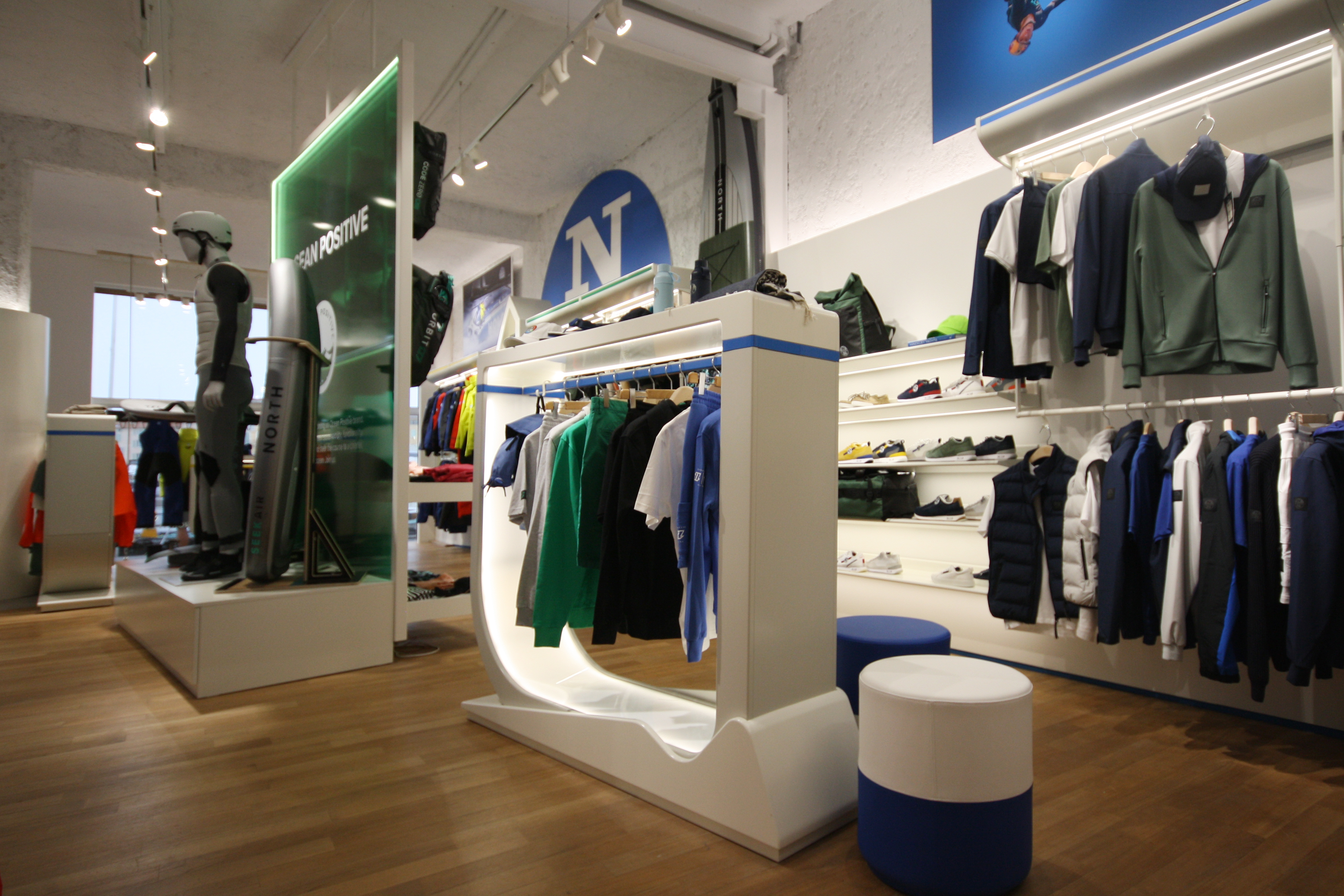 Curved white retail corridor with North Sails logo and outerwear display — VANDA+Marcel design