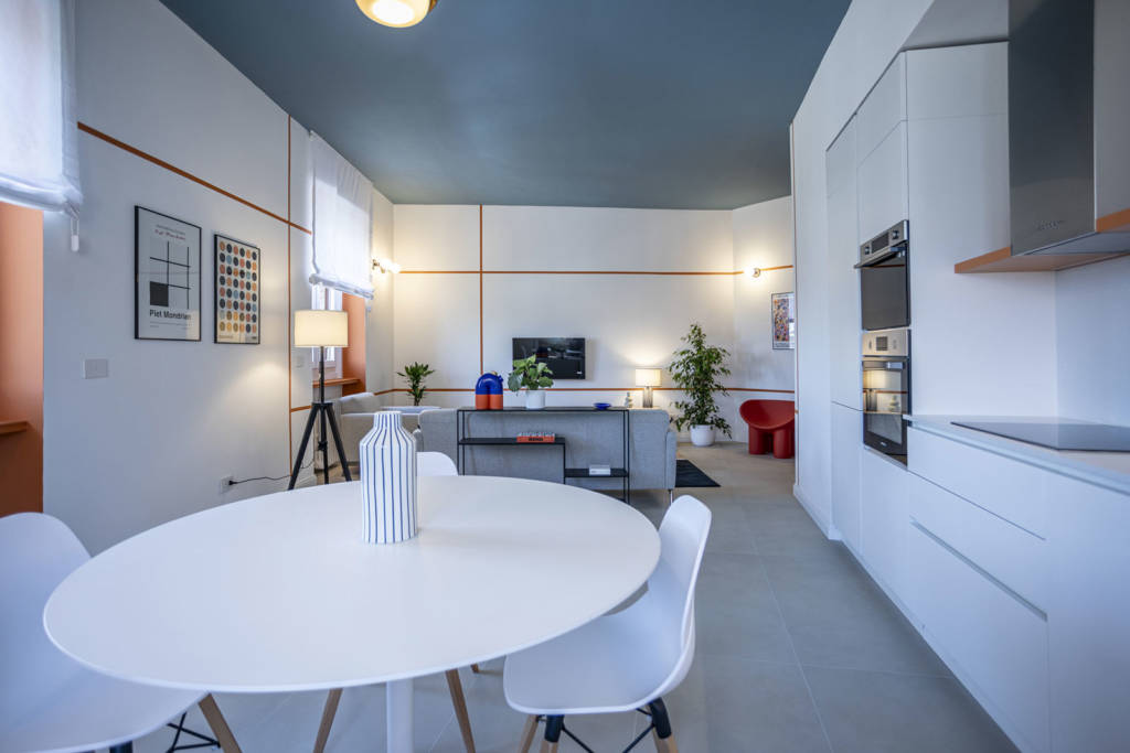 Compact apartment Milan - dining area with round white table and open kitchen