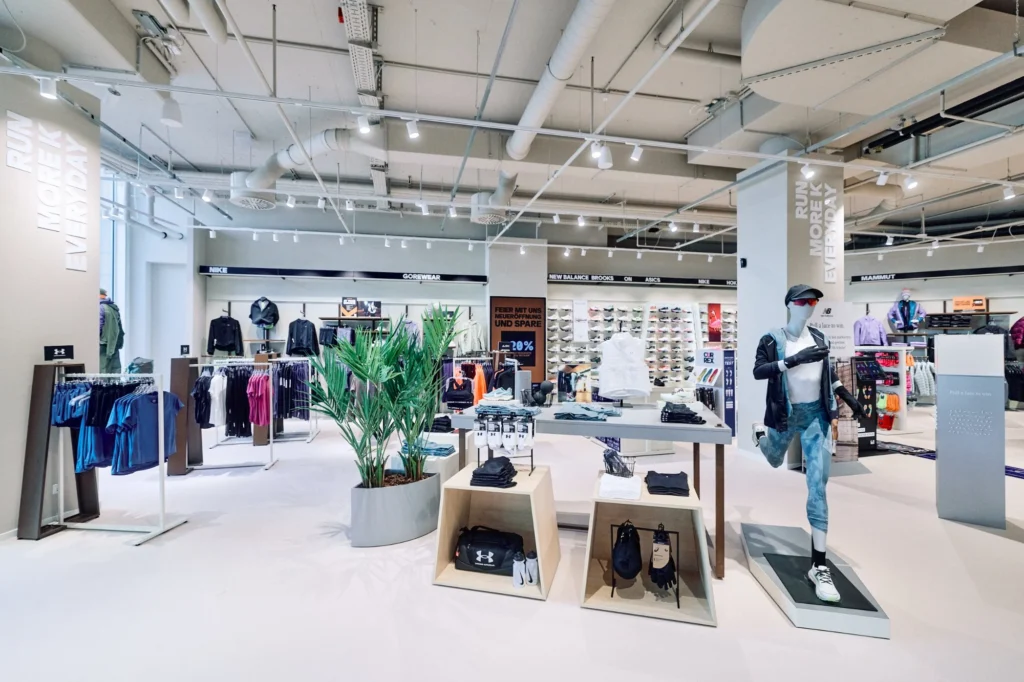 Women’s area of the SportScheck flagship in Dortmund with light wood fixtures and warm lighting, designed by VANDA in 2025