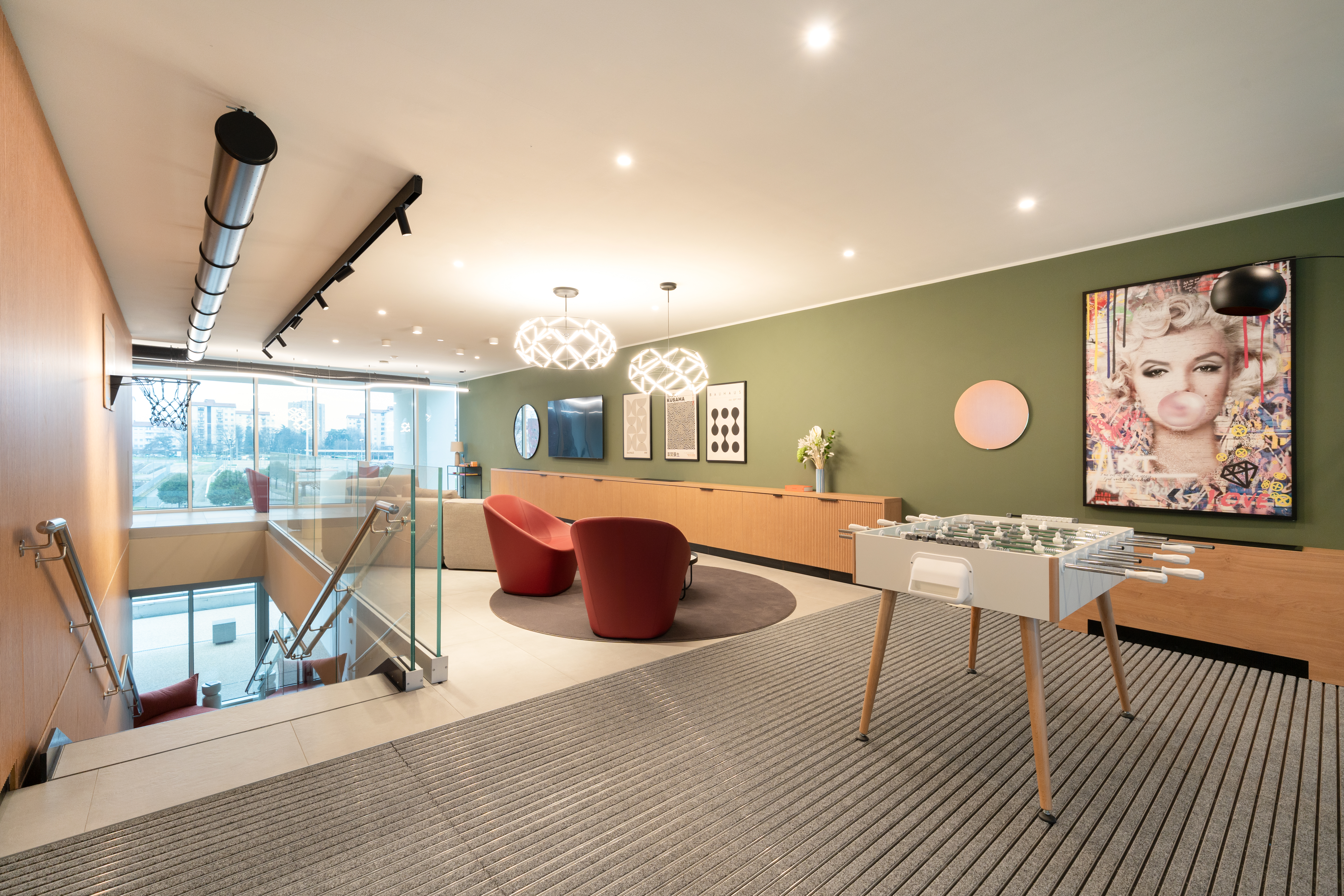 LivinUp SeiMilano clubhouse, soggiorno con divani e opere d'arte su parete verde salvia, interior design amenities Milano