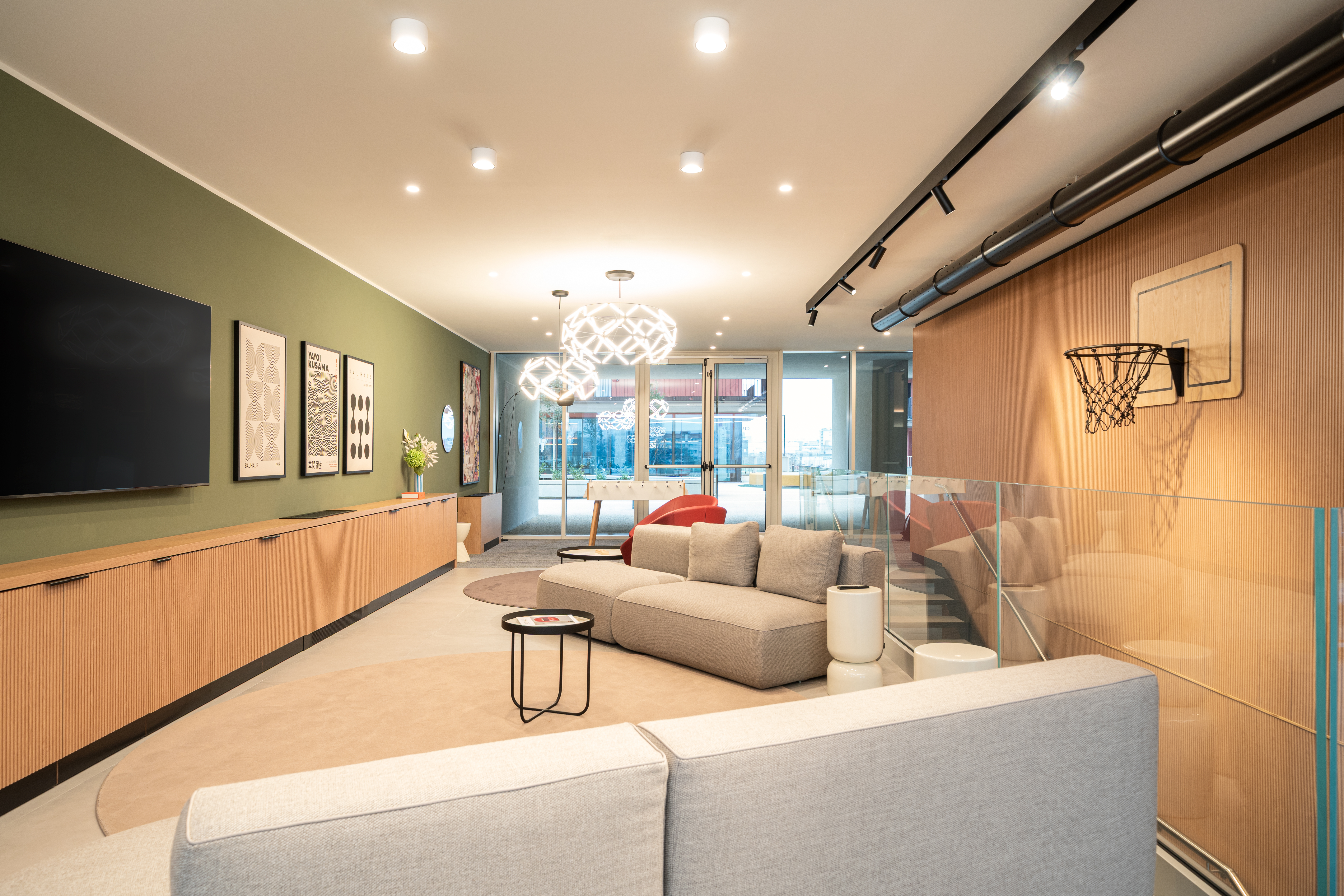 LivinUp SeiMilano clubhouse, area soggiorno con boiserie in rovere e dettagli rosso ciliegia, interior design amenities Milano