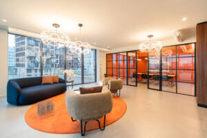 LivinUp SeiMilano coworking, lounge area with city view and orange details, interior design amenities Milan