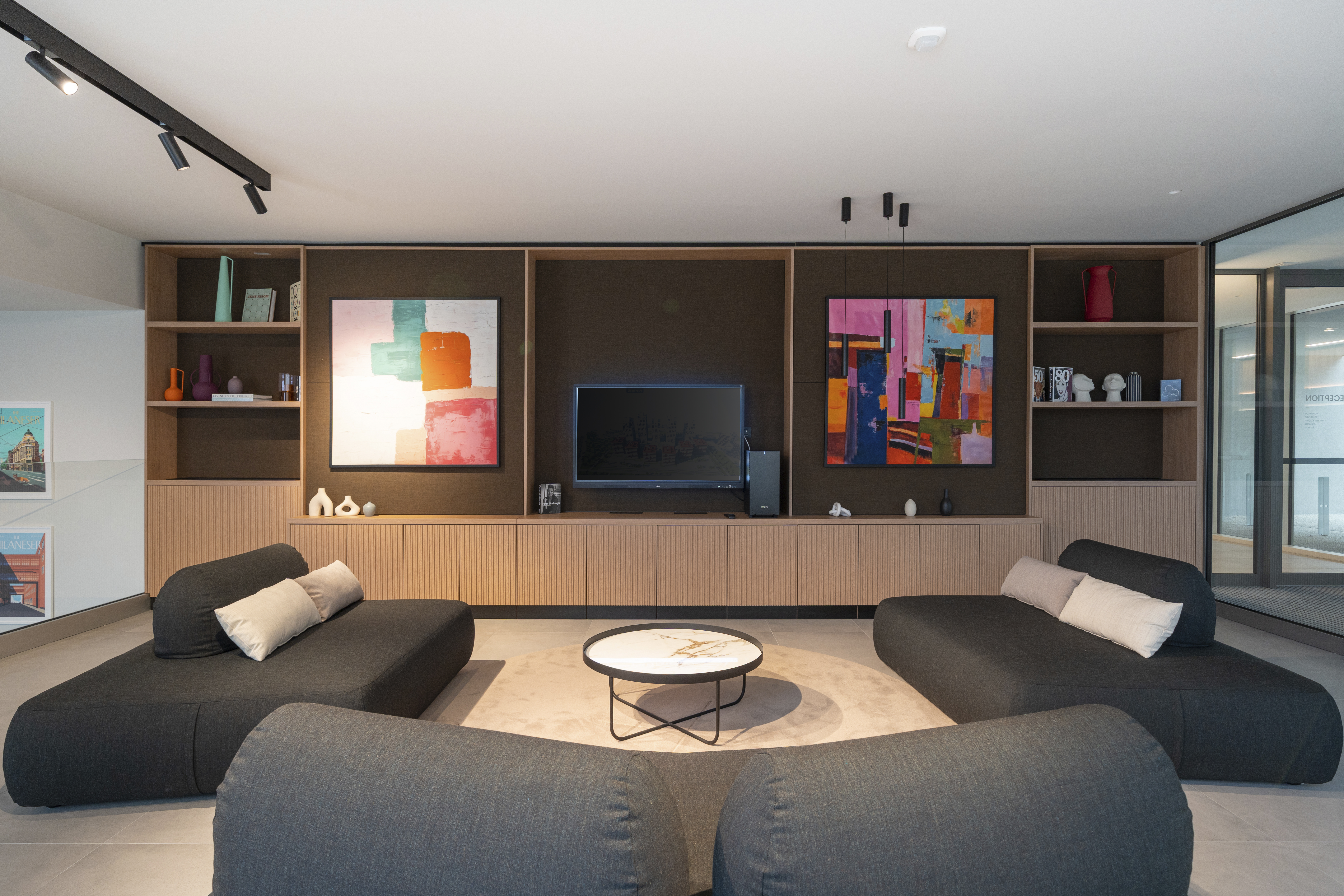 LivinUp SeiMilano portineria con divani scuri, libreria su misura e opere d'arte, interior design amenities Milano