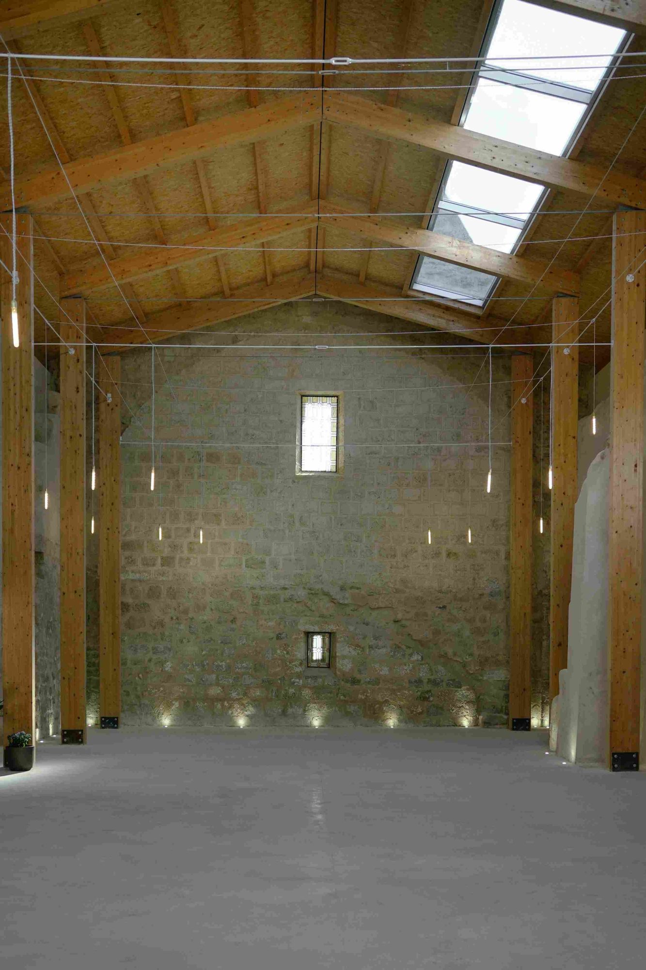 Nave of La Nueva San Pedro with glulam trusses, skylights and stone wall