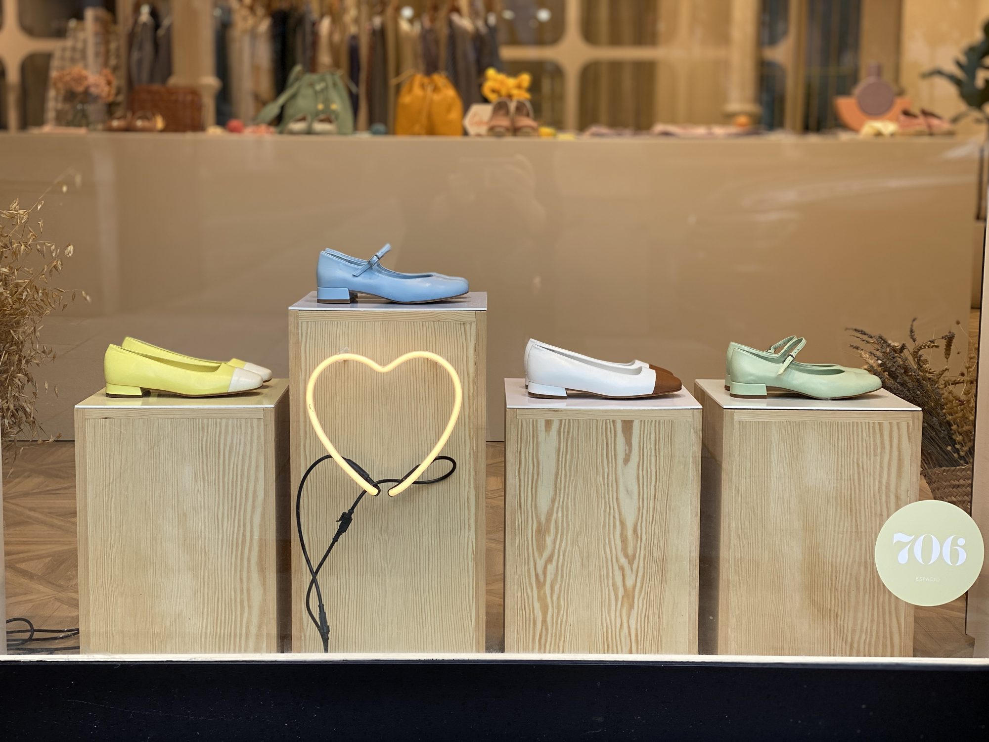 Pocca window with pastel ballet flats on pine plinths and a neon heart
