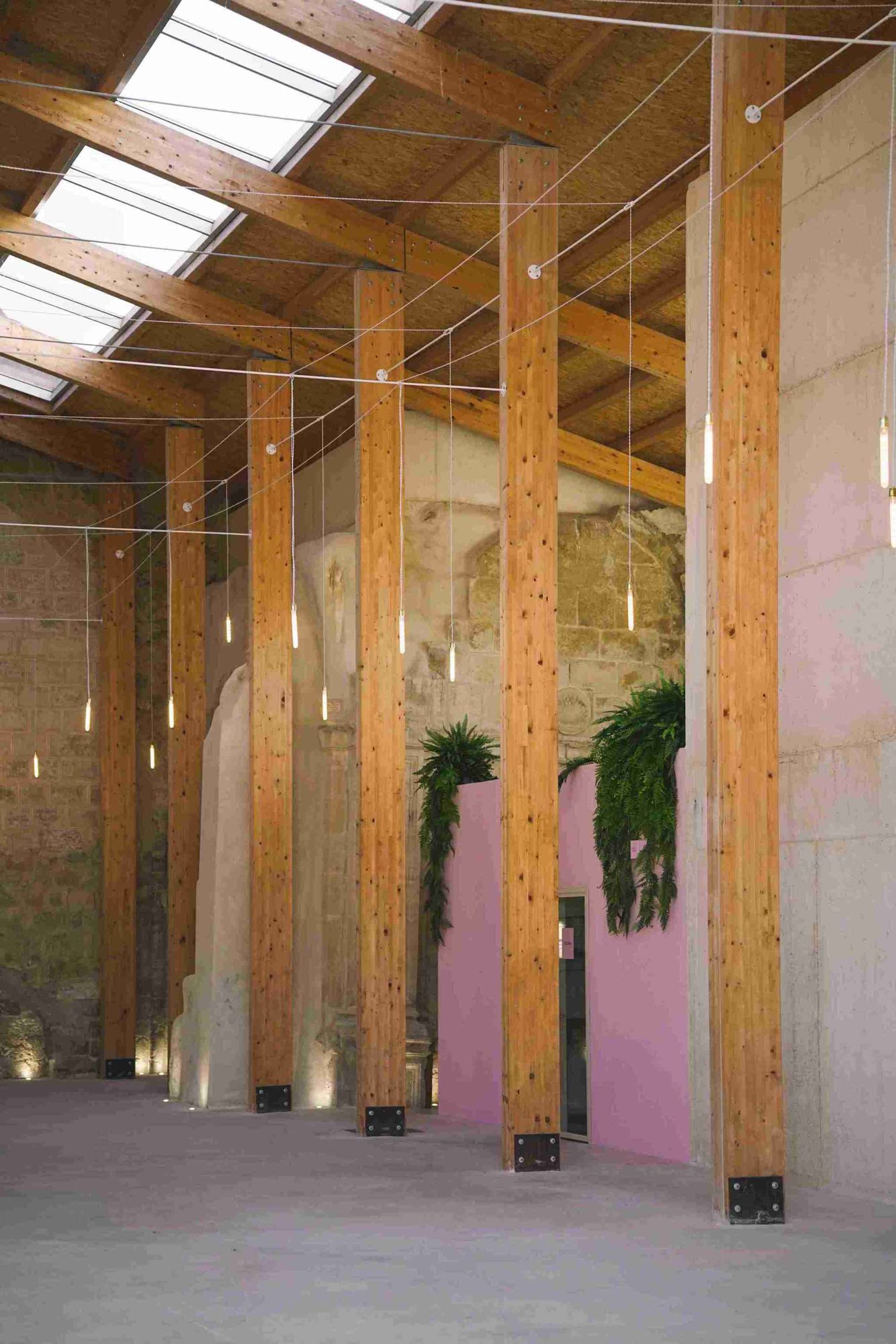 Glulam columns and pink volume with ferns inside the restored church