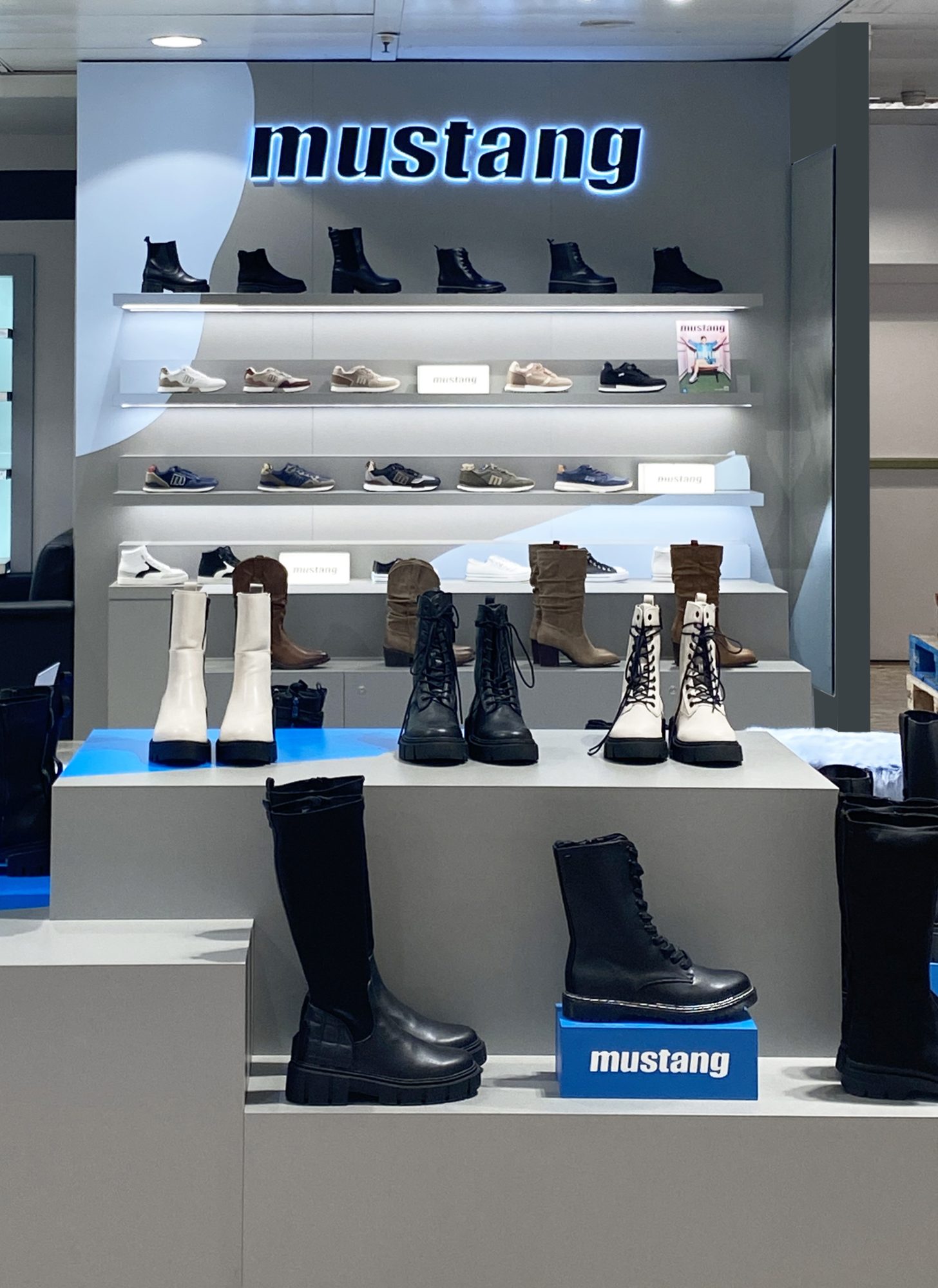 Stepped grey plinths with Mustang boots in front of the display wall
