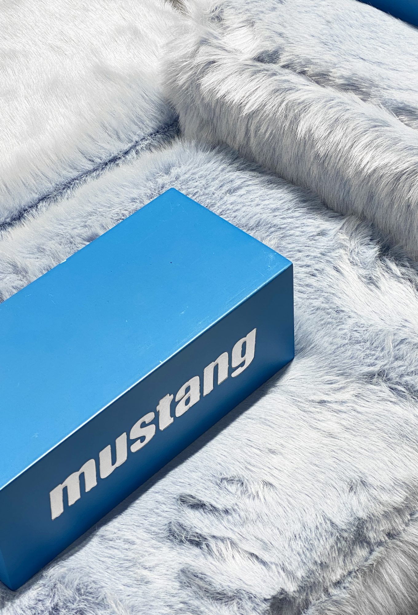 Blue Mustang logo cube on white and grey ecological fur