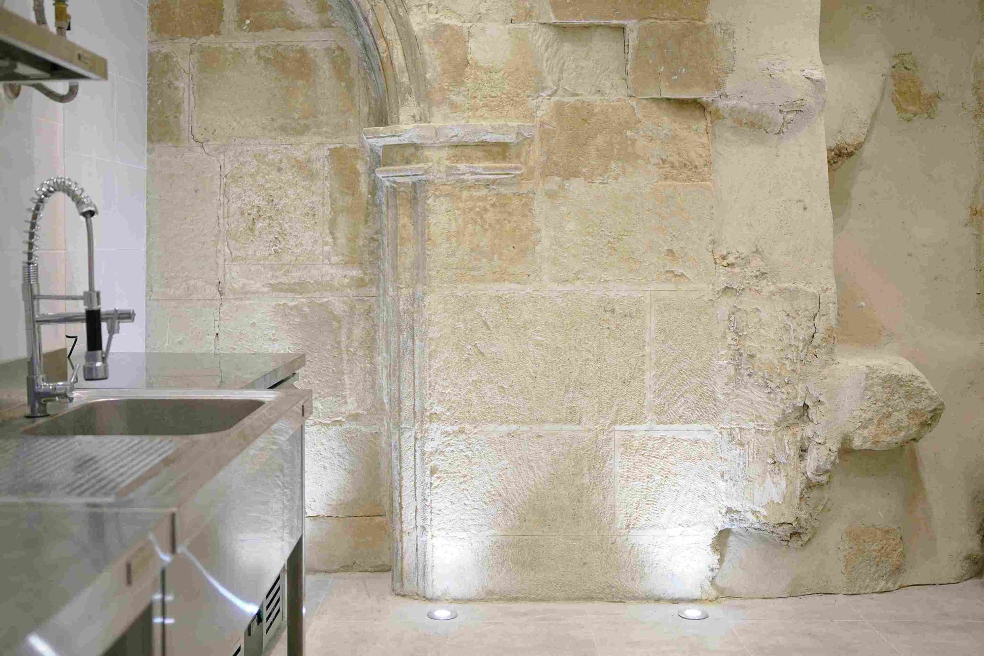 Original stone arch lit from below next to the stainless steel kitchen